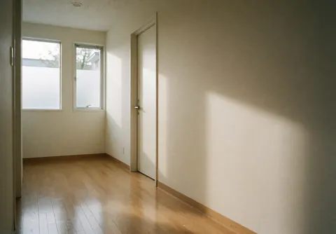 A clean and bright hallway with wooden floors, beige walls, and natural light coming through a window, creating a calm and professional atmosphere for a healthcare facility.