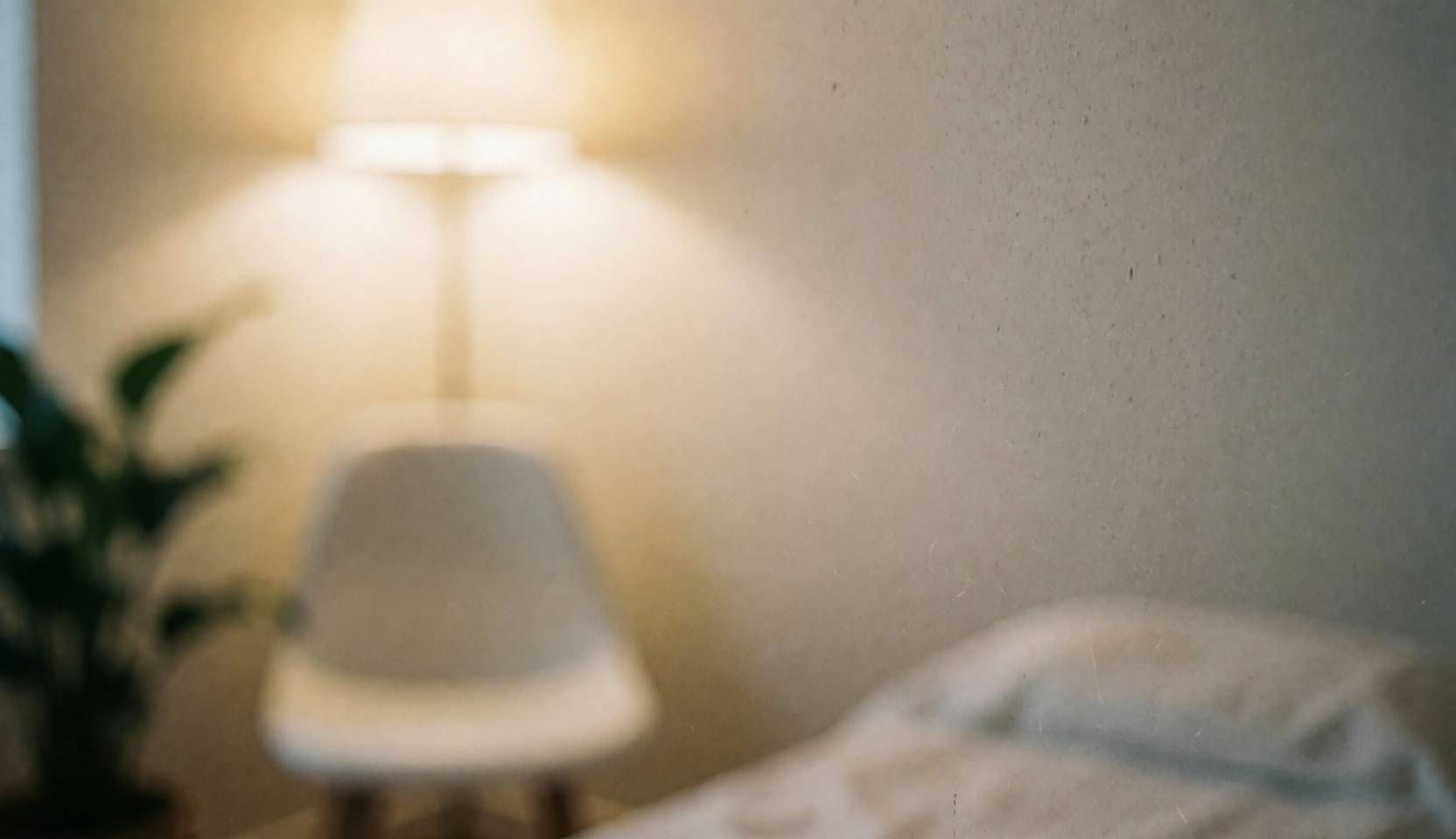 Soft focus interior background featuring a chair and green plant, suitable for text overlay in osteopathy and wellness contexts