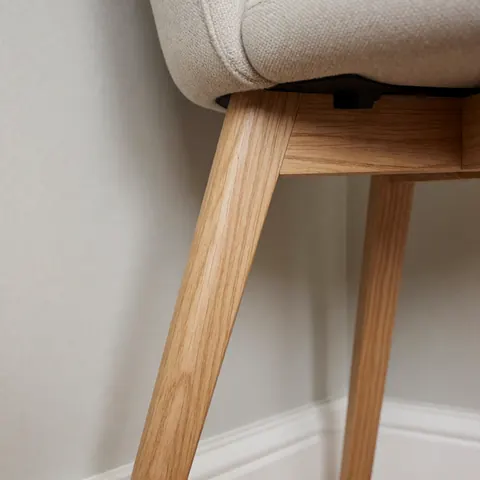 Detailed view of a wooden chair joint being repaired with a dowel, highlighting the natural wood grain and sturdy construction for home furniture restoration.