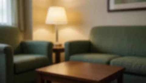 A warm waiting area featuring green sofas, a wooden coffee table, and a lamp, creating a calm atmosphere ideal for wellness and reiki text backgrounds.