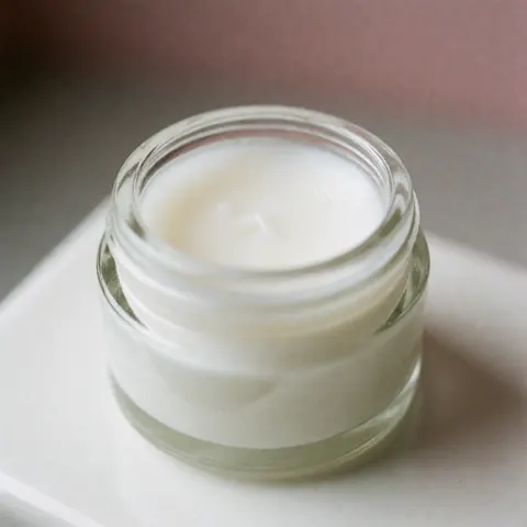 White keratolytic balm in a glass jar on a white surface, ideal for podiatry and foot and hand care products.