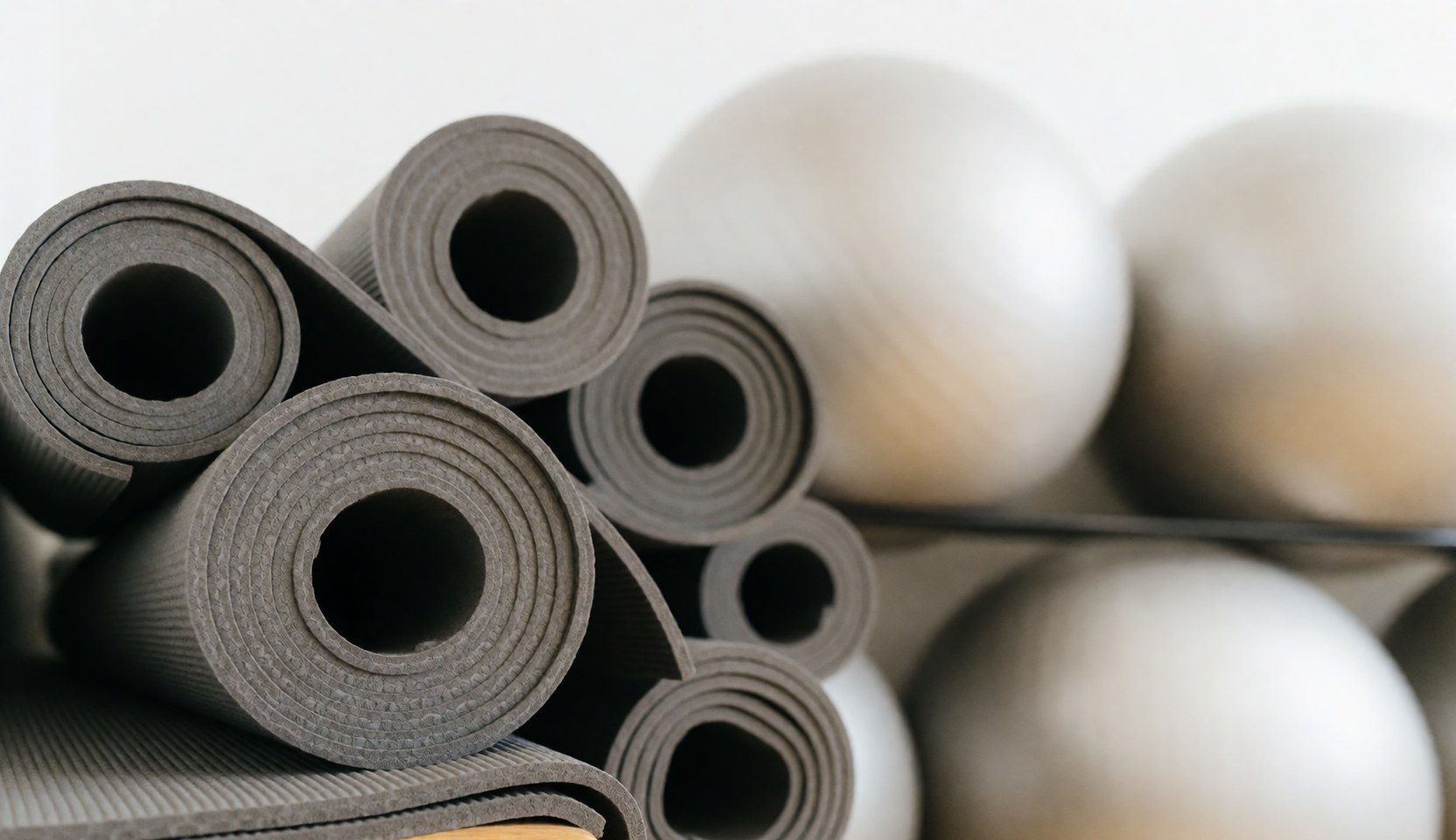 A yoga mat and stability balls arranged on a clean, neutral background suitable for text overlay in wellness and therapy contexts