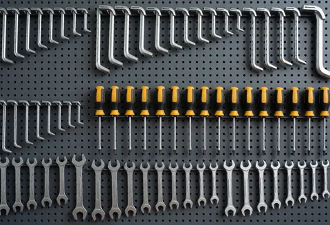 Neatly arranged bicycle repair tools including wrenches, screwdrivers, and tube keys mounted on a pegboard wall in a clean professional workshop.