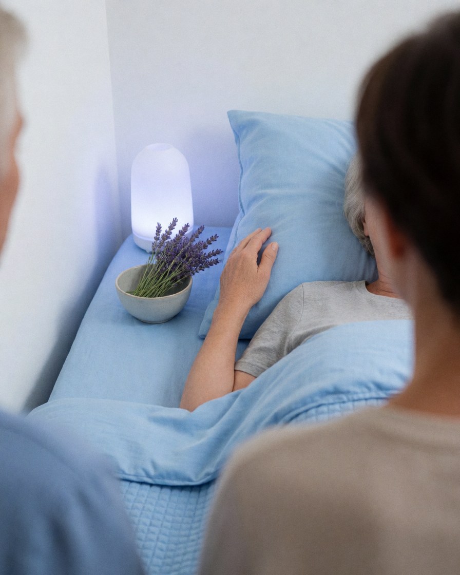 A person resting in bed with lavender and an aromatherapy diffuser, enjoying calm relaxation in a softly lit room with blue sheets.