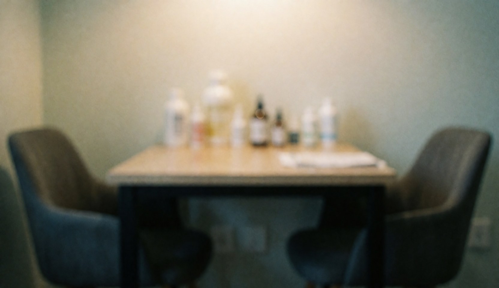 A softly blurred background of a quiet consultation space featuring neutral tones, wooden elements, and essential oil bottles, ideal for aromatherapy business websites