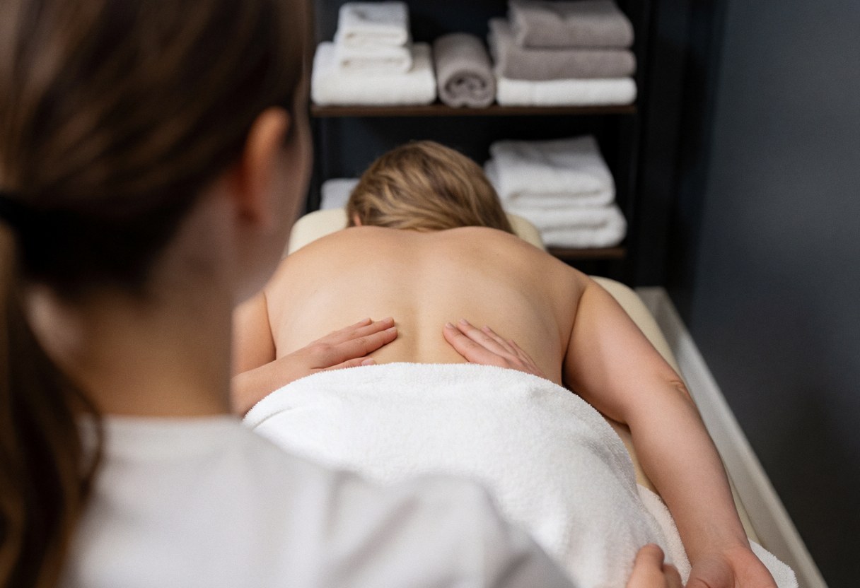 Therapist performing chiropractic massage on a client's back on a table with towels in the background