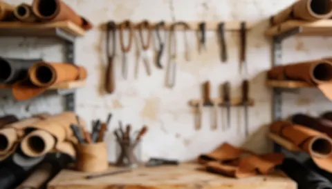 Out of focus leather workshop background featuring hanging tools, leather rolls, and a work table, ideal for commercial text overlays.