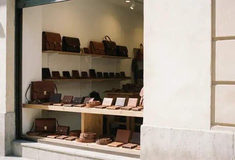 A wooden display case showcasing leather handbags in a storefront window, highlighting quality craftsmanship and elegant design for business use