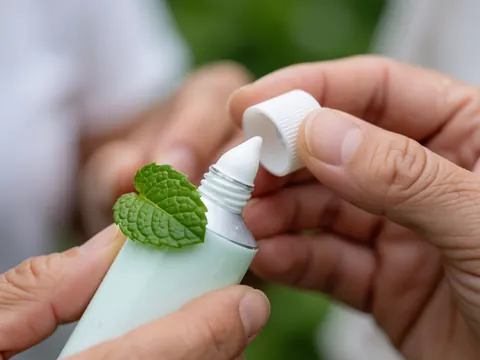 Close-up view of smooth mint cream texture featuring a fresh green mint leaf for natural relief and acupuncture wellness