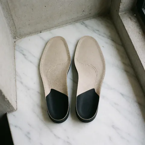Close-up view of custom anatomical insoles placed on a white marble surface with natural diffuse lighting, highlighting ergonomic design for foot care and reflexology products.