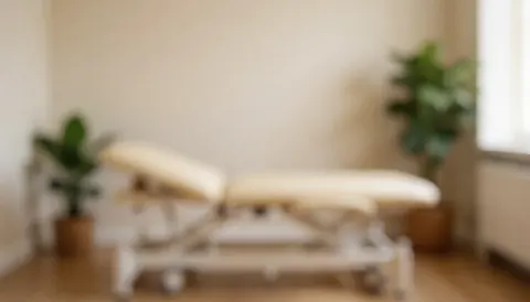 Soft background of a therapy room featuring a massage bed, green plants, and warm lighting, suitable for wellness and health text overlays.