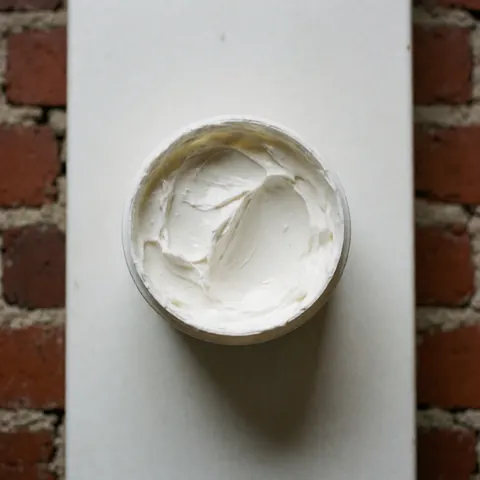 Open tube of foot cream viewed from above on a red brick surface with a clean texture suitable for reflexology salons