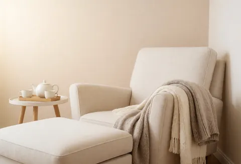A comfortable beige armchair and side table with a teapot and cup in a calm interior space with natural light