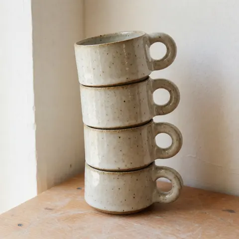 A neat stack of white ceramic coffee mugs arranged vertically, showcasing their simple design and smooth texture for product display purposes.
