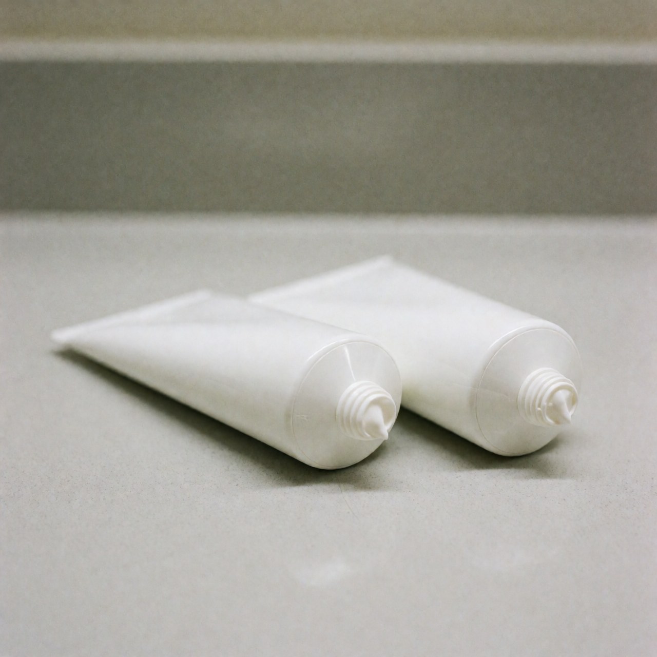 Several tubes of therapeutic cream arranged neatly on a clean white countertop with soft lighting and a blurred background, suitable for osteopathy and post-treatment care products.