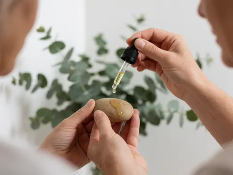Close-up view of clear eucalyptus essential oil droplets resting on a smooth, warm hot stone used in spa therapy