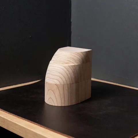 Close-up of a wooden heel block used in shoemaking, showing natural wood grain and texture for footwear repair work