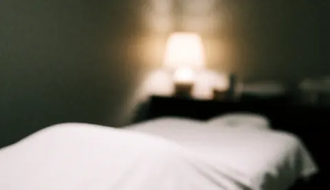 Softly focused white bed in a room with warm lighting, serving as a serene background for acupuncture treatment text.
