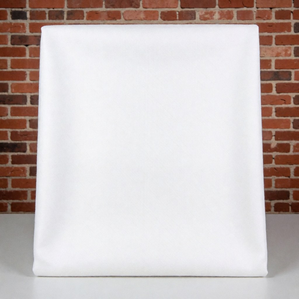 Close-up view of a white cotton textile fabric folded neatly on a surface, showcasing its soft texture and clean appearance for product display.