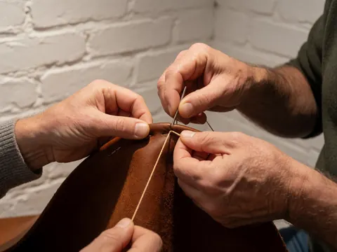Detailed view of brown leather stitching with visible thread and needle work on a textured surface