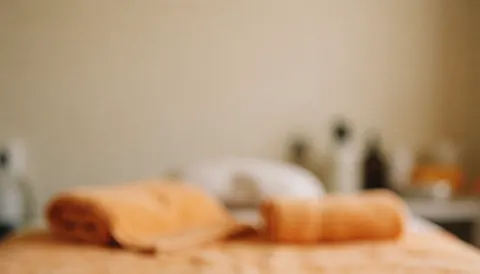 Warm-toned spa background featuring orange towels and bottles, ideal for massage and wellness text overlays