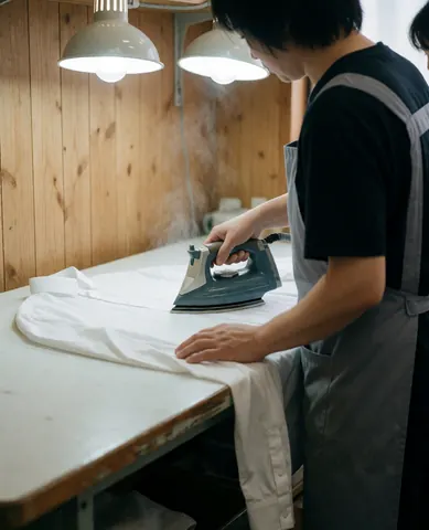 Close-up view of a professional ironing process on a wooden board, highlighting the care and precision involved in garment maintenance for business attire.