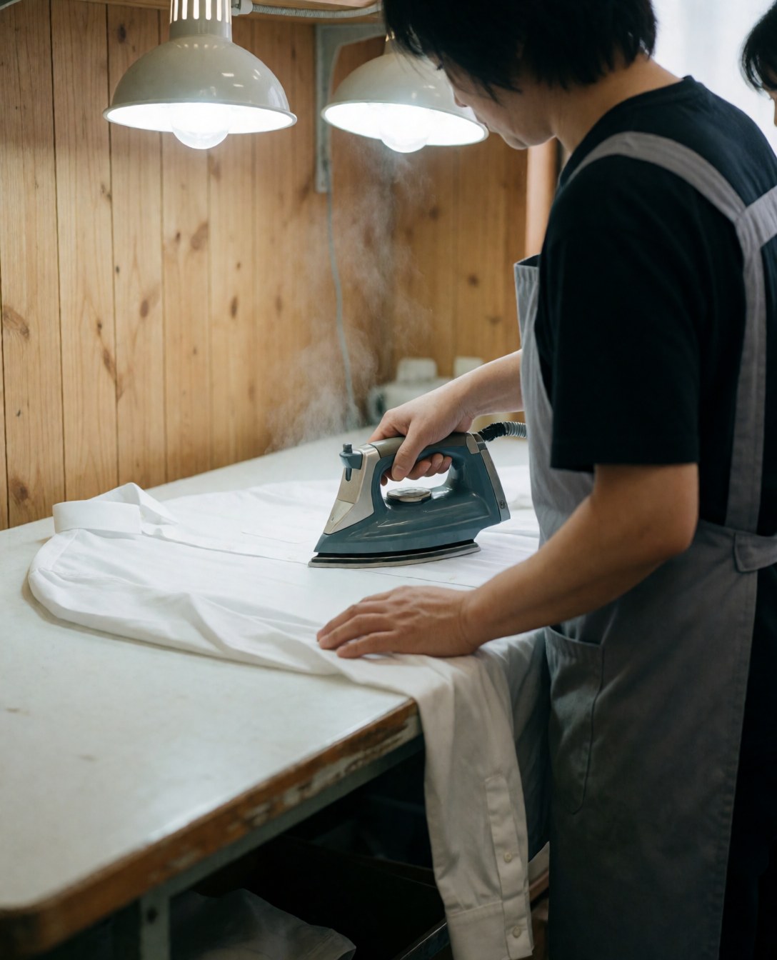 Close-up view of a professional ironing process on a wooden board, highlighting the care and precision involved in garment maintenance for business attire.