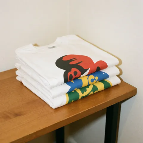 Finished custom printed t-shirts arranged on a wooden table with a white background for product display