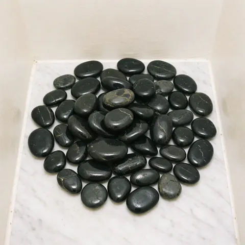Smooth black basalt stones arranged for a relaxing hot stone massage treatment in a spa setting