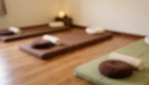 Warm-toned background featuring soft Thai massage cushions and pillows on a wooden floor, ideal for promotional text overlays.