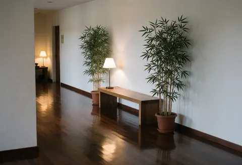 Tranquil spa entrance hallway featuring polished dark wood floors, a wooden bench, tall bamboo plants, and soft lighting for a relaxing atmosphere.