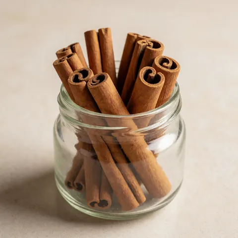 A collection of cinnamon sticks stored inside a clear glass jar, showcasing natural spices for traditional healing and culinary use.