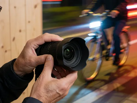 A close-up view of a photographer's hands adjusting and preparing a wide-angle camera lens for professional use