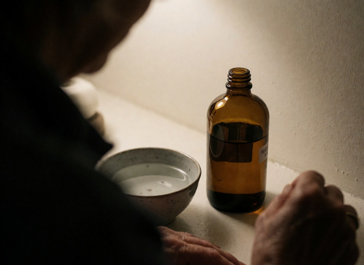 Glass bottle of essential oil and a cup of water arranged for shiatsu therapy, promoting relaxation and holistic wellness in a calm setting.