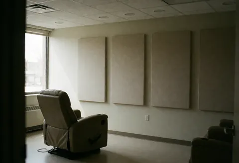 A calm hypnotherapy induction room featuring a recliner chair, acoustic panels, and natural light for relaxation