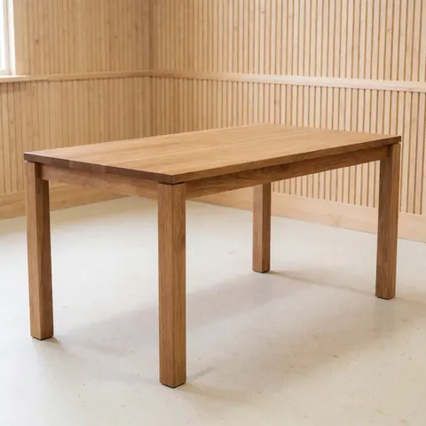 Close-up of a finished solid wood dining table with natural grain, displayed in a carpentry workshop setting for furniture product photography