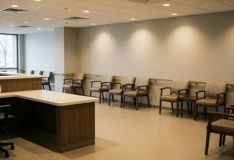 Empty accessible reception with armchairs, low counter, warm gray walls, and soft lighting for senior care centers