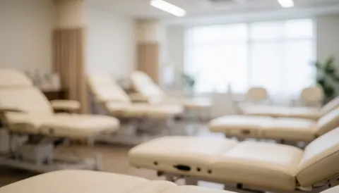 Out of focus background showing beige reclining treatment beds in a professional studio with natural light, ideal for text overlay.