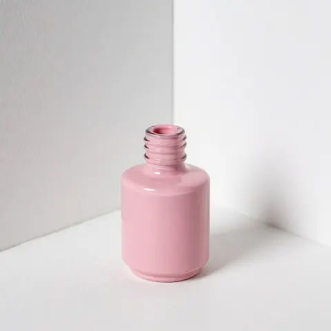 Open pink nail polish bottle placed on a white surface with soft lighting and a clean white background for beauty salon product display