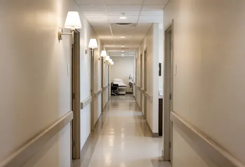Well-lit sterile hallway in a piercing studio featuring treatment beds and neutral walls for aesthetic business use