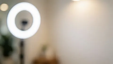 Soft blurred background with white ring light and neutral wall, ideal for beauty service text overlays