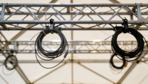 Metal truss background with coiled cables for event lighting, suitable for text overlays and technical service descriptions