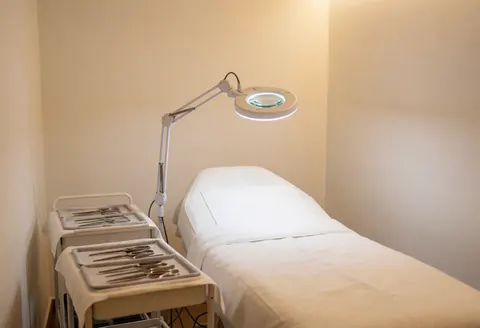 Clean and professional acne treatment room featuring magnifying lights, sterile beds, and instrument trays ready for skin care procedures.