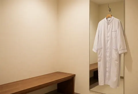 Wood bench and white coat reflected in mirror in private clinic room with warm lighting