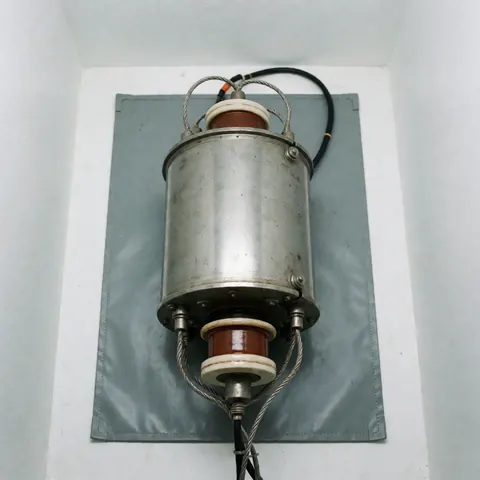 Microwave magnetron with ceramic insulators and wires on a gray anti-static mat against white walls with clinical lighting