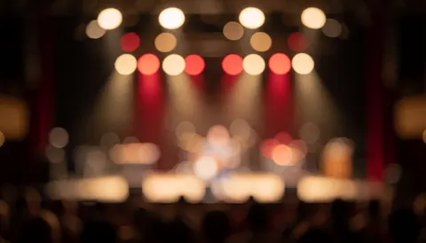 Warm red stage lights in soft bokeh blur, creating a professional background ideal for overlaying text without visible people