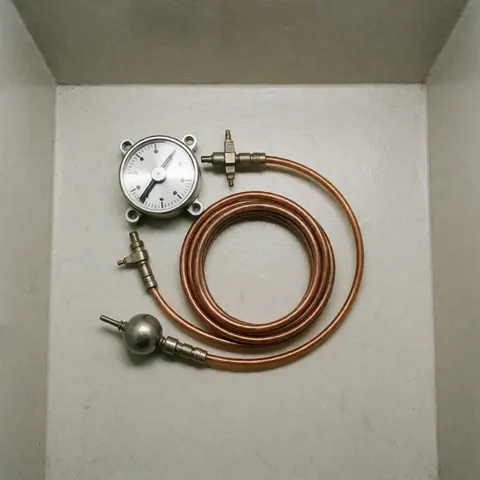 Capillary thermostat with copper tube and metal bulb on white background, a component for refrigerator repair