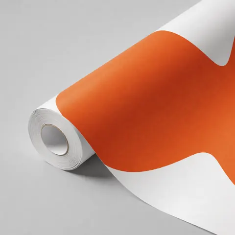 Partially unrolled bright orange decorative vinyl roll placed on a neutral gray surface for modern interior design