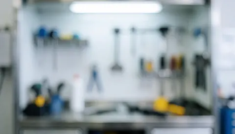 Out-of-focus background of a computer repair shop featuring hanging tools and a workbench under neutral lighting, suitable for text overlay