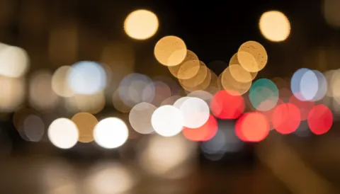 Warm toned bokeh background of blurred city car lights at night, suitable for text overlays and graphic design projects.